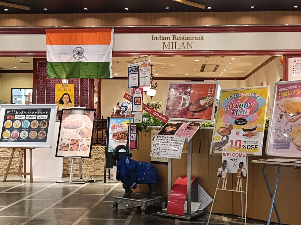 Vegetarian Curry in Nagasaki: Indian Restaurant MILAN at Nagasaki Station Entrance of Indian Restaurant MILAN on the 5th floor of Amu Plaza Nagasaki, with an Indian flag and menu boards including Turkish rice
