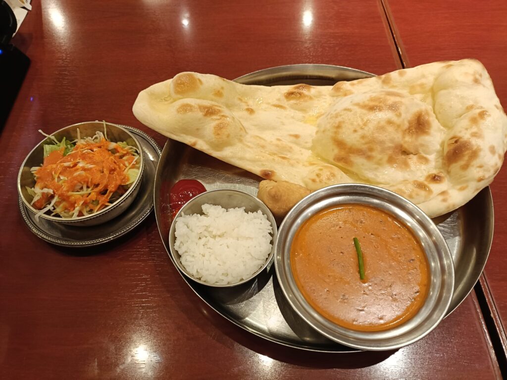 A vegetarian curry set at Indian Restaurant MILAN, with naan bread, rice, mixed dal curry, a vegetable samosa, and a side salad