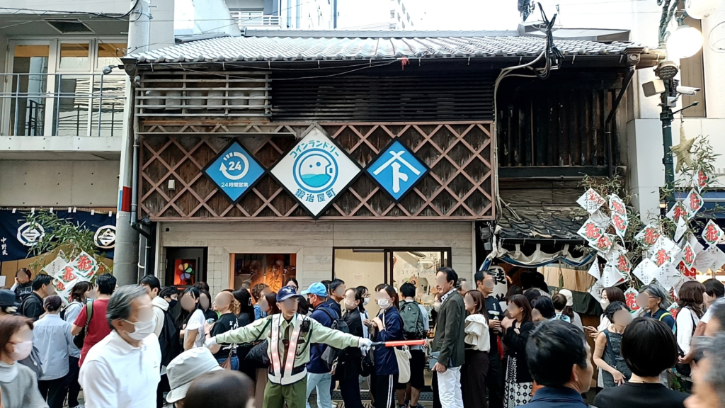 Crowds lined up outside a coin laundry housed in an old wooden townhouse in Kajiya-machi, Nagasaki, on the evening of Niwamise