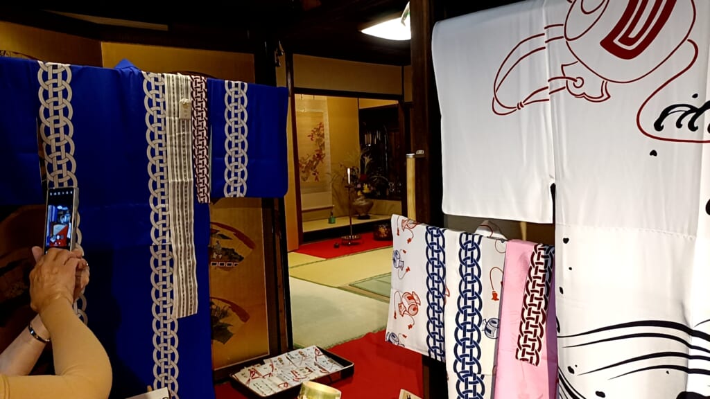 Festival costumes hung at the entrance of a tatami room, with a gold folding screen and a hanging scroll behind them