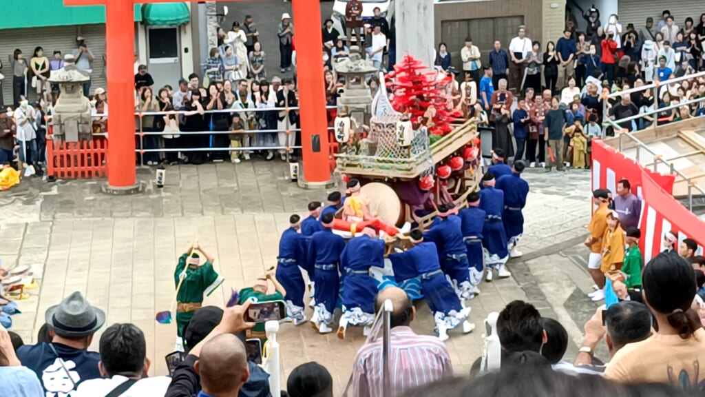 Men in blue costumes pushing Aburaya-machi's kawafune float around during Niizoroi, with spectators watching from all sides