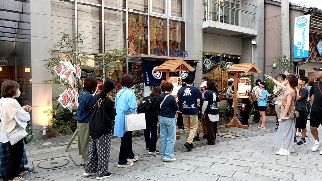 People lining up outside the Nakanoya flag shop in Kajiya-machi, Nagasaki, during Niwamise